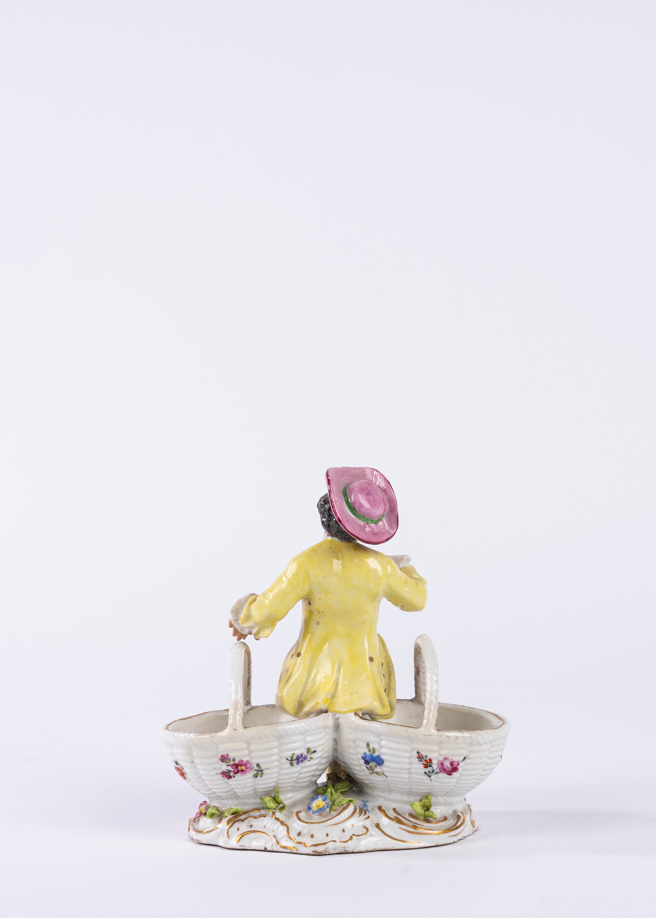 Saliera in porcellana policroma in forma di giovane gentiluomo seduto tra due cestini in finto vi...