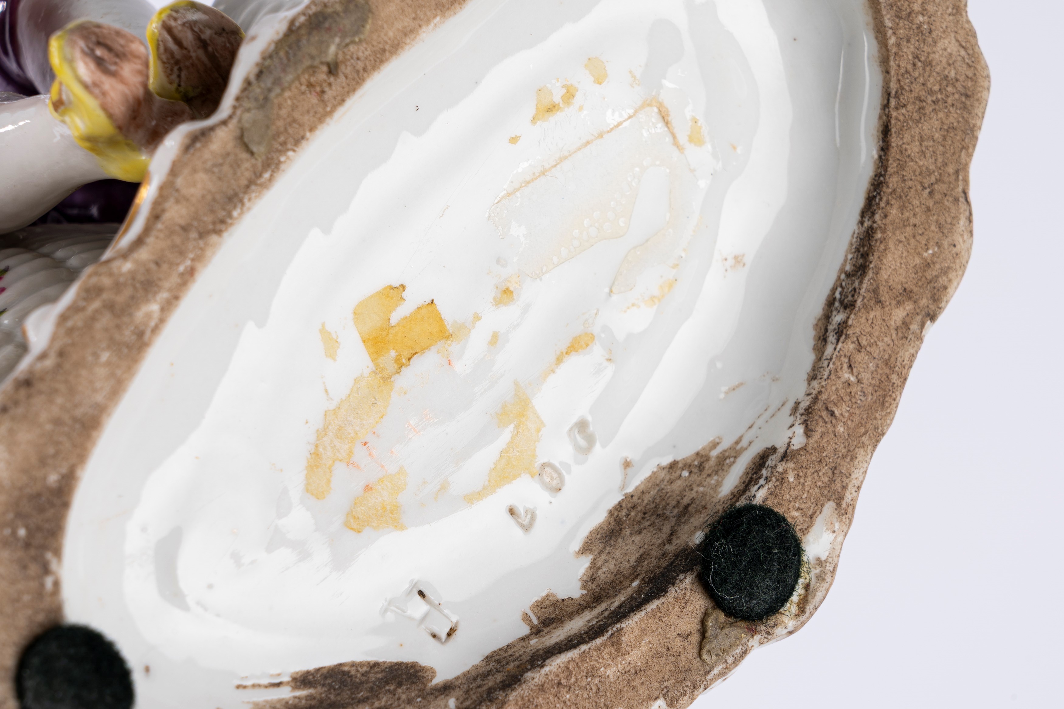 Saliera in porcellana policroma in forma di giovane gentiluomo seduto tra due cestini in finto vi...