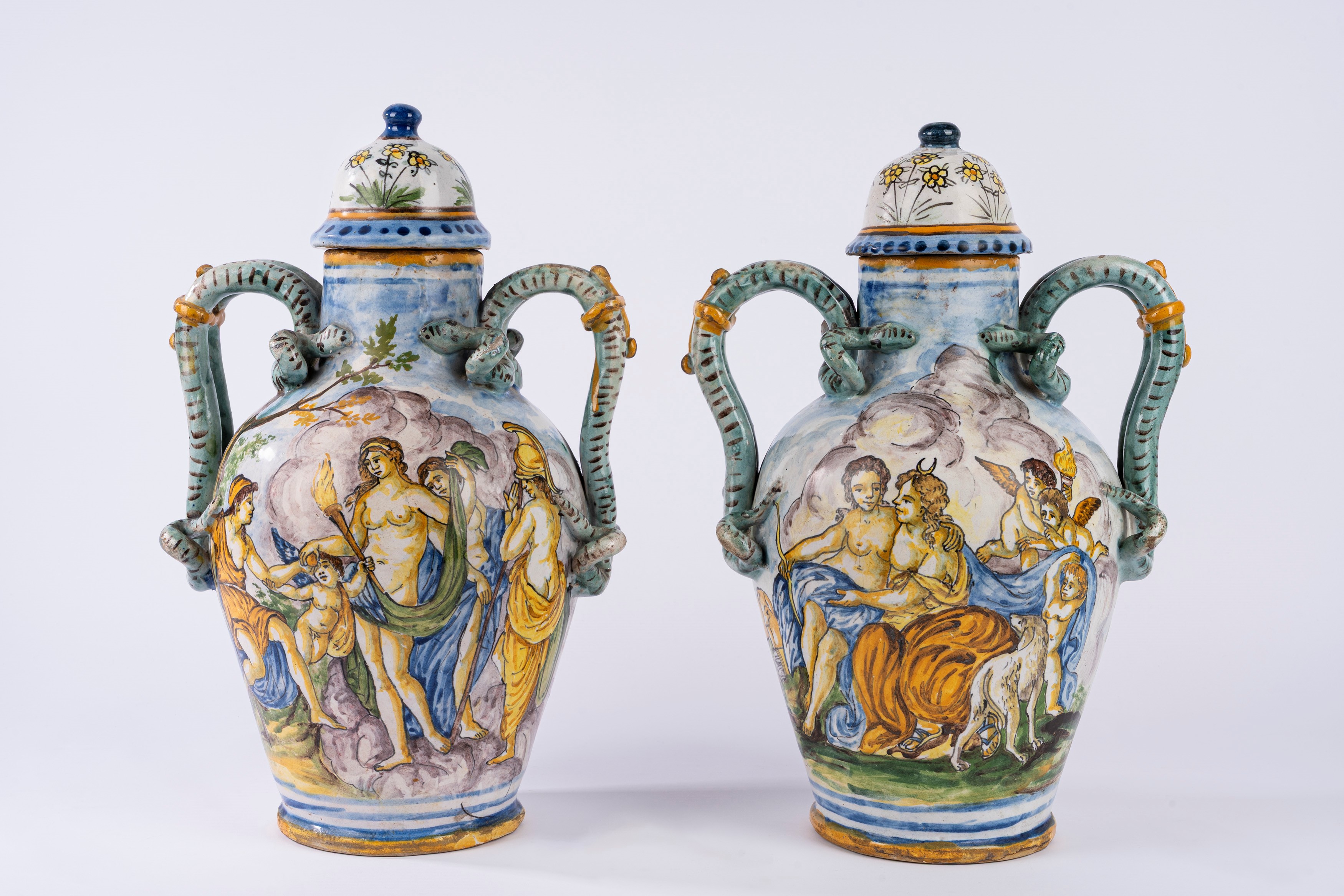 Coppia di vasi ad anfora con coperchio in maiolica policroma istoriata a scene mitologiche con an...