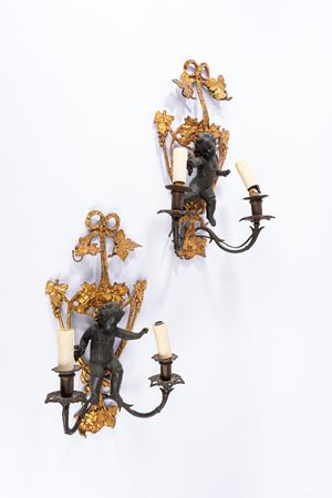 Pair of two-light wall sconces in gilded and patinated bronze with a stand decorated with a cherub in relief. 18th or 19th century.