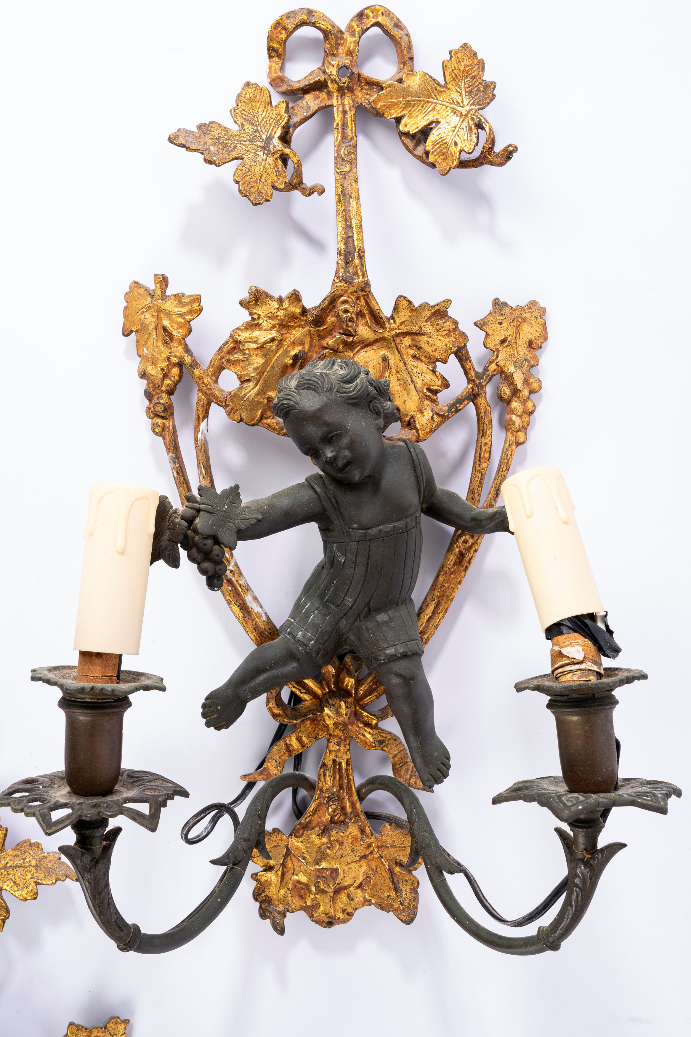 Coppia di appliques a due luci, bronzo dorato e patinato con putto a rilievo, XIX secolo