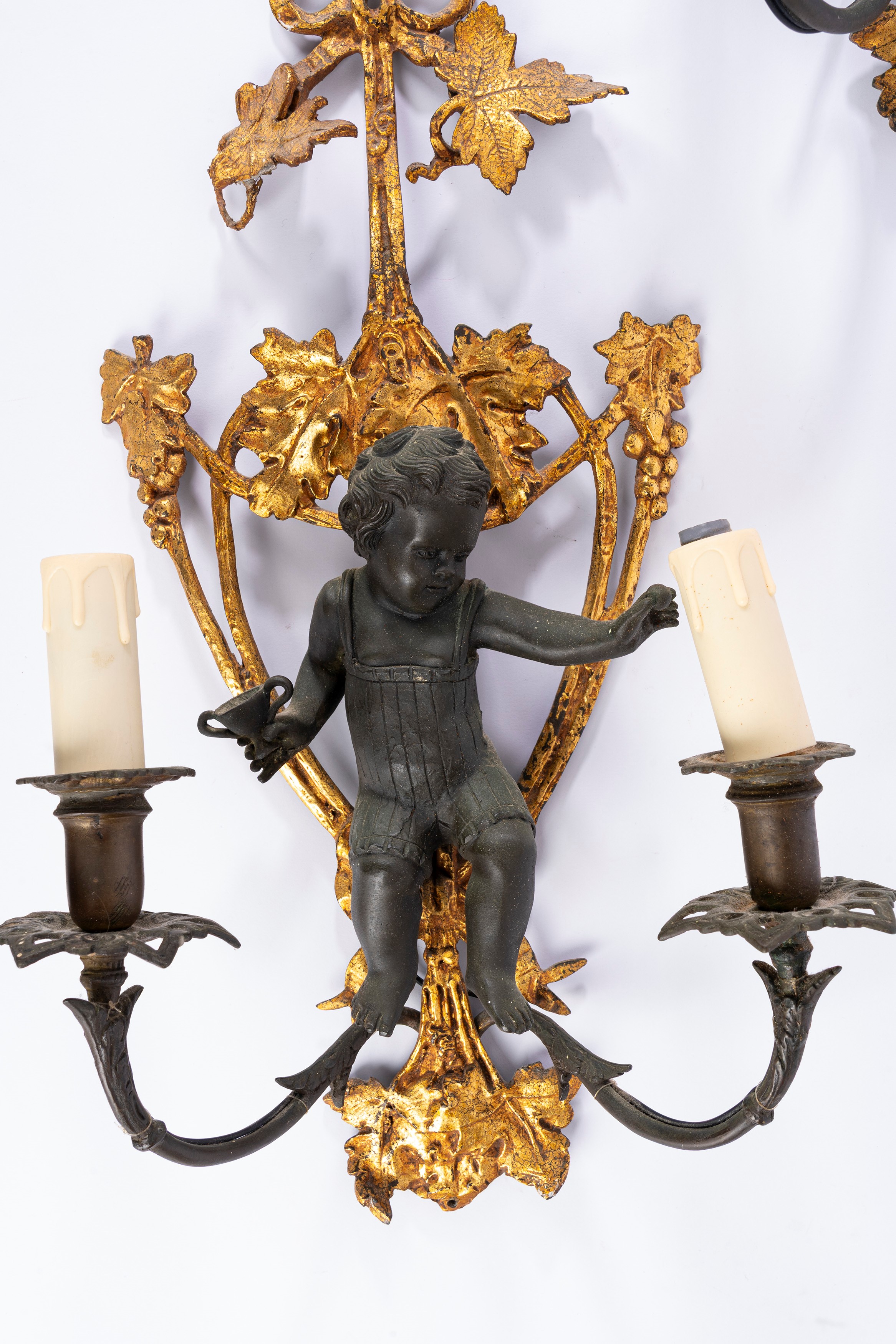 Coppia di appliques a due luci, bronzo dorato e patinato con putto a rilievo, XIX secolo