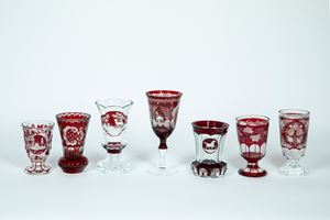 Lot of seven clear and burgundy crystal glasses decorated with different floral and naturalistic motifs.