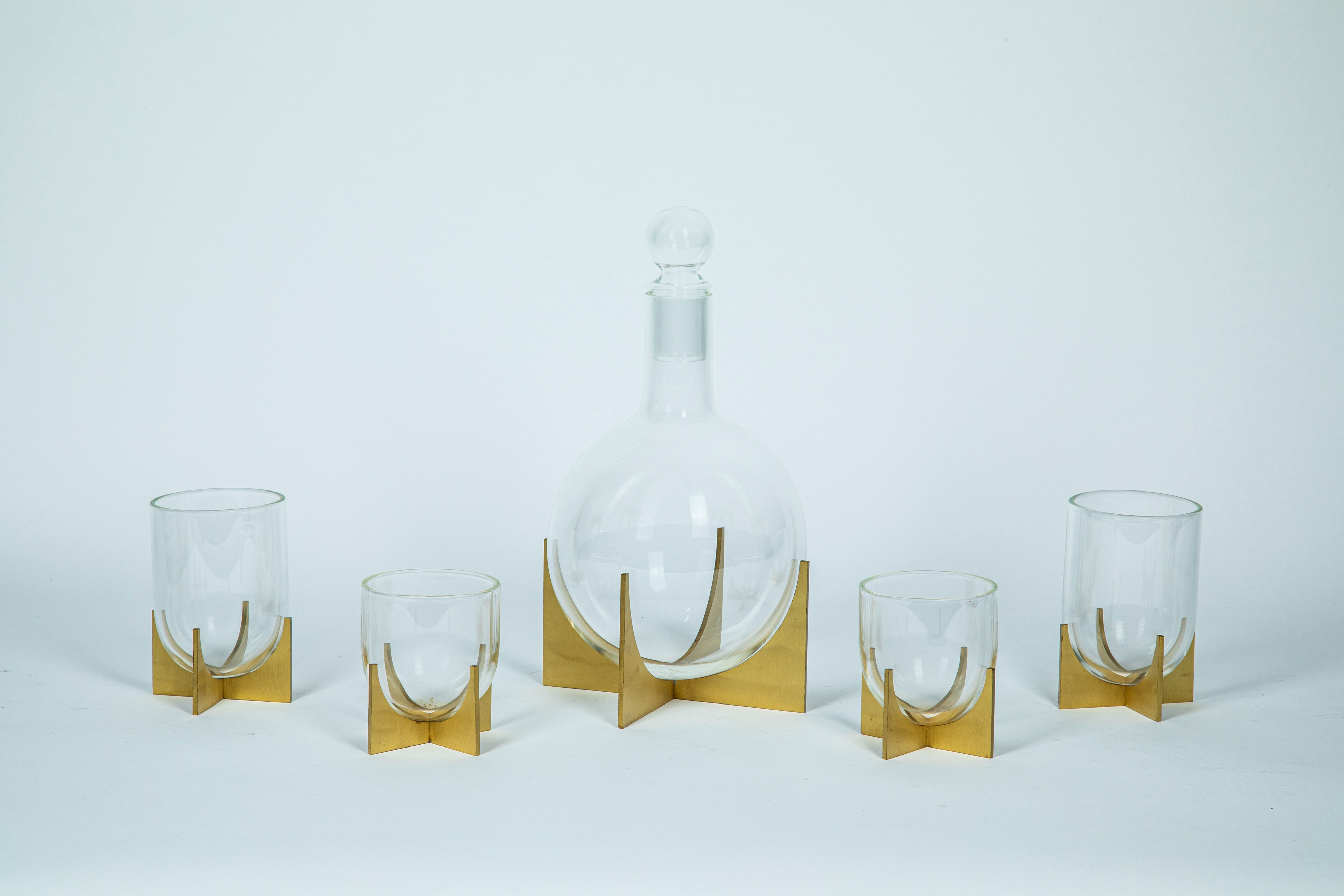 Decanter and four glasses in colorless blown glass on a brass stand ...