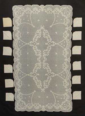 Tovaglia di forma rettangolare in cotone a pelle d'uovo a bordo mosso ricamata con due medaglioni floreali centrali e con ghirlande di fiori lungo il bordo, con dodici tovaglioli 