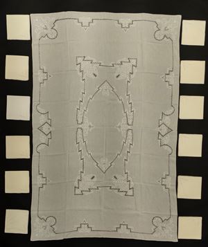 Tovaglia rettangolare in mussola di lino con medaglione centrale e bordo ricamato e traforato a motivo geometrico stilizzato