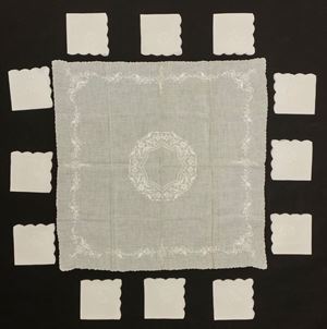 Small square linen cocktail tablecloth embroidered with flowers and leaves with a central medallion and twelve napkins with a similar wavy edge decoration