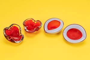 Quattro posaceneri: due a forma di trifoglio in vetro incolore e rosso e due a forma ovale in vetro policromo rosso e azzurro