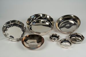 Lotto composto da sette centrotavola in metallo argentato di forme e misure differenti pi&ugrave; un vaso e una brocca con manico in legno ebanizzato