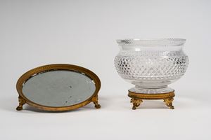 Centrotavola con parte superiore semisferica in cristallo molato poggiante su base di gusto &ldquo;Impero&rdquo; in bronzo cesellato unito ad un centrotavola di gusto &ldquo;impero&rdquo; di forma circolare con fondo a specchio e supporto in bronzo dorato con piedini cesellati fine secolo XIX - Inizio secolo XX