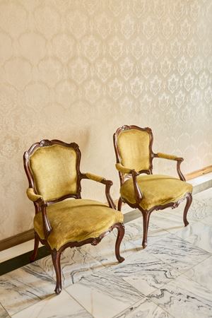 Coppia di poltrone in legno intagliato con braccioli mossi terminanti a ricciolo, schienale e grembiale centrati da valva di conchiglia. Veneto, secolo XVIII