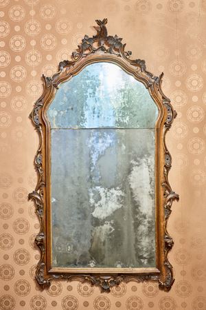 A curved mirror in carved walnut with openwork friezes of leafy scrolls. Veneto, 18th century.