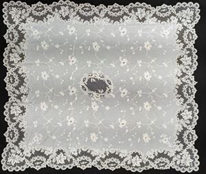 Tovaglia in lino e pizzo bianco a profilo mosso con ricami a motivi floreali. Inizio secolo XX