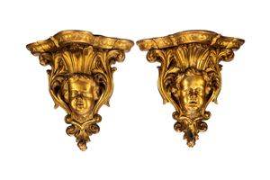 Coppia di console pensili in legno intagliato e dorato con sostegno a testa di putto tra volute di foglie. Secolo XIX