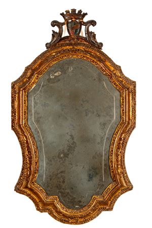 Specchiera di forma mossa con cornice in legno intagliato e dorato, cimasa a stemma. Secolo XIX