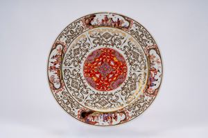 Piatto in porcellana decorata con dorature ad arabeschi e in policromia con medaglione centrale a &ldquo;salami&rdquo; (indianische blumen). Meissen, 1730-1735.  