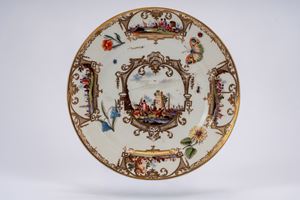 MPiatto in porcellana bianca decorata con dorature e in policromia a scene portuali entro riserve tra fiori, farfalla e insetti sparsi. Meissen, 1740 circa.