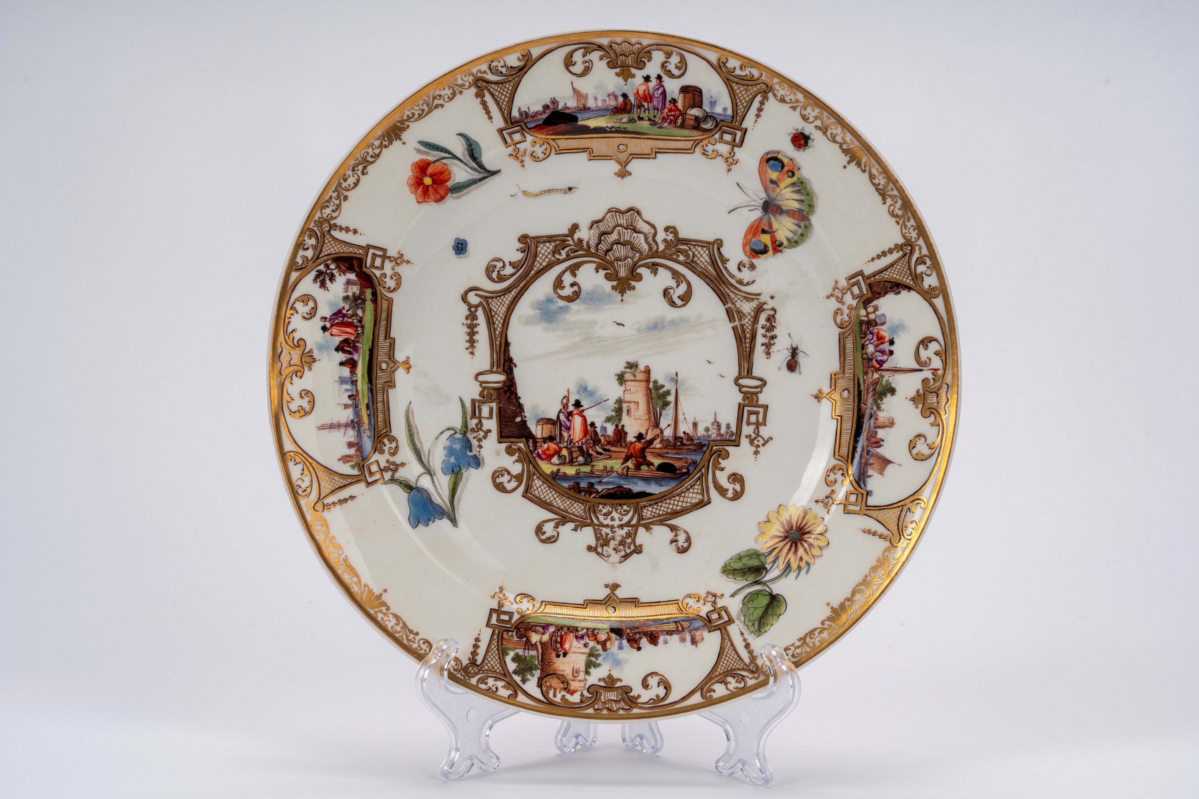 Meissen (attrib.), Piatto in porcellana bianca con scena portuale entro riserve dorate e policrom...