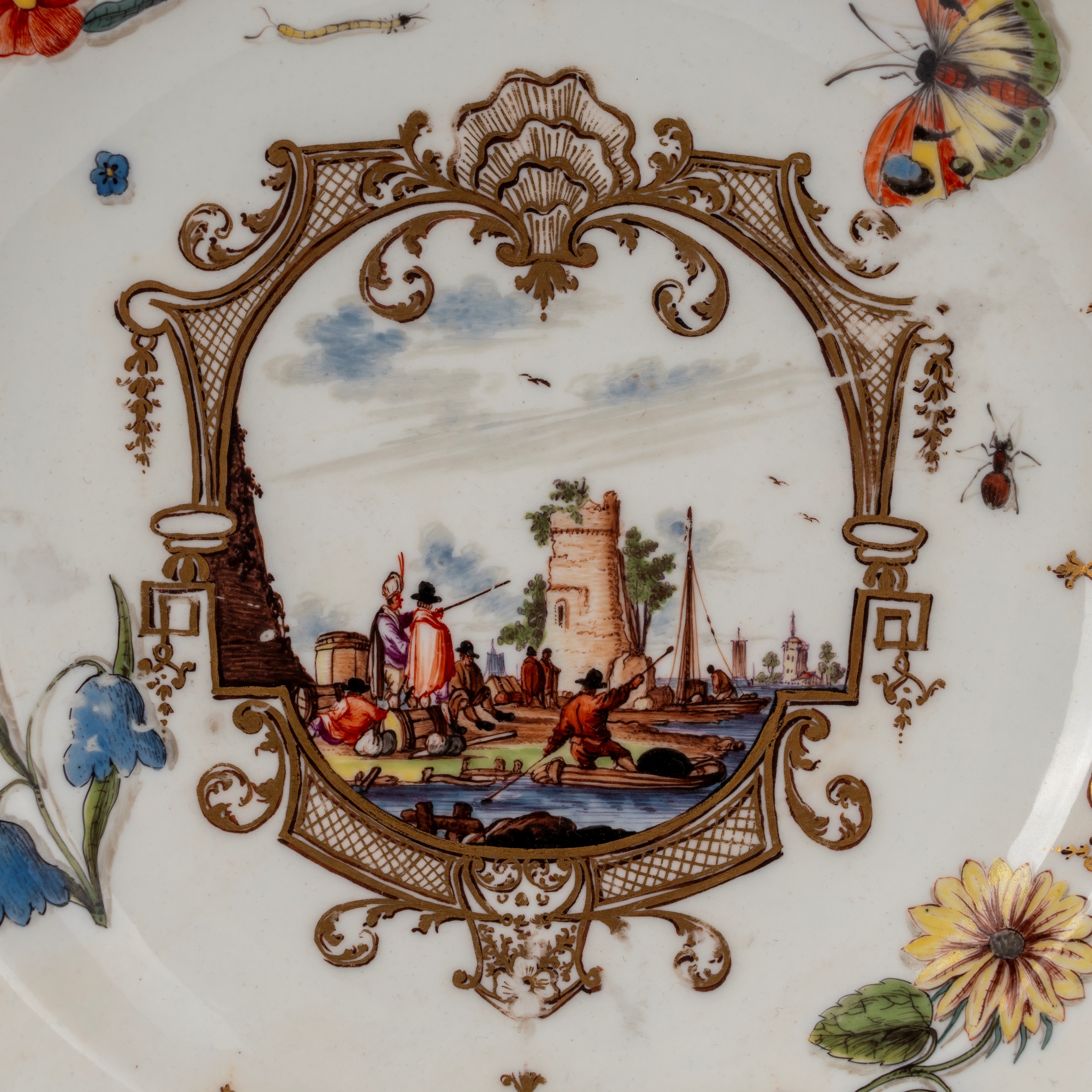 Meissen (attrib.), Piatto in porcellana bianca con scena portuale entro riserve dorate e policrom...
