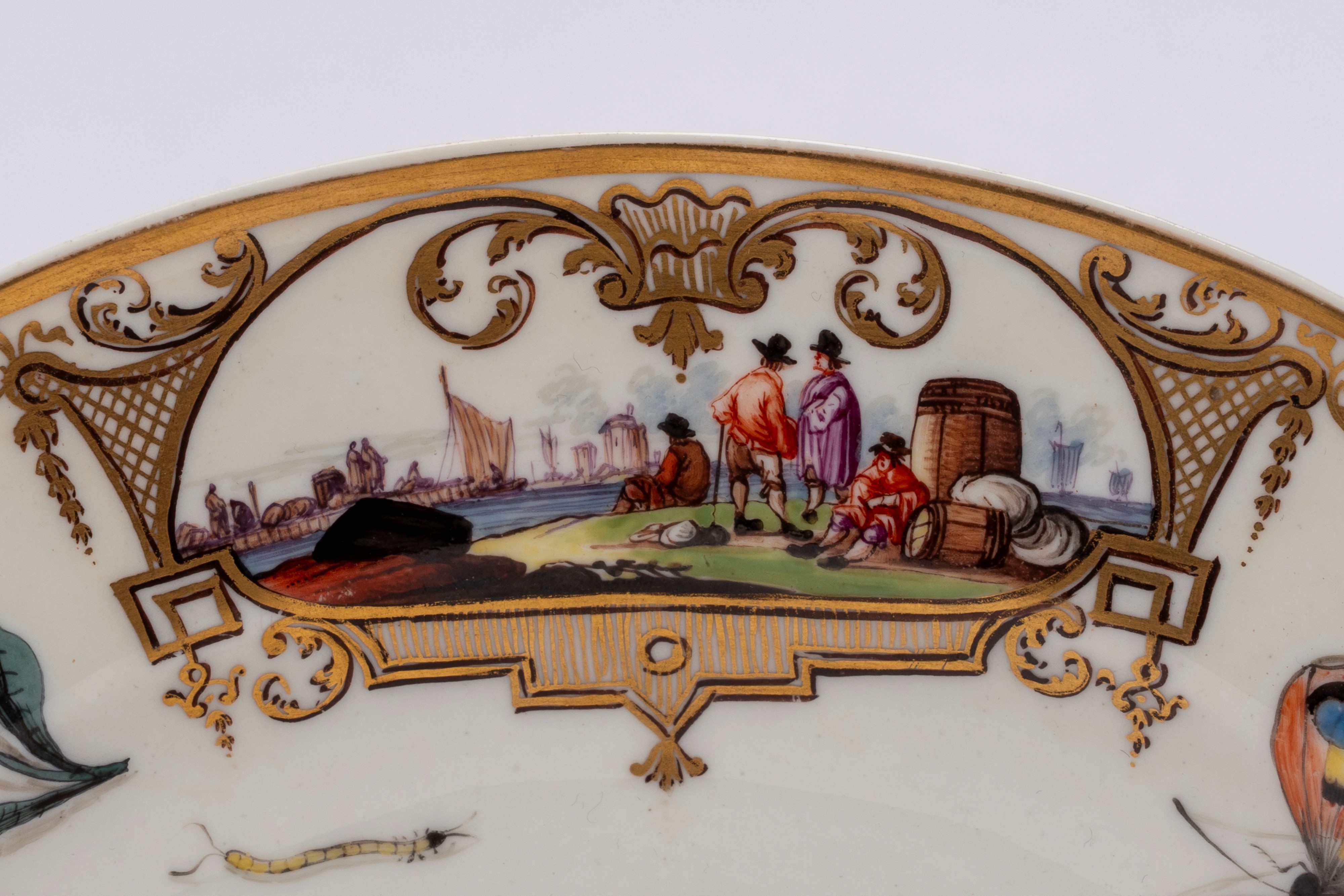 Meissen (attrib.), Piatto in porcellana bianca con scena portuale entro riserve dorate e policrom...