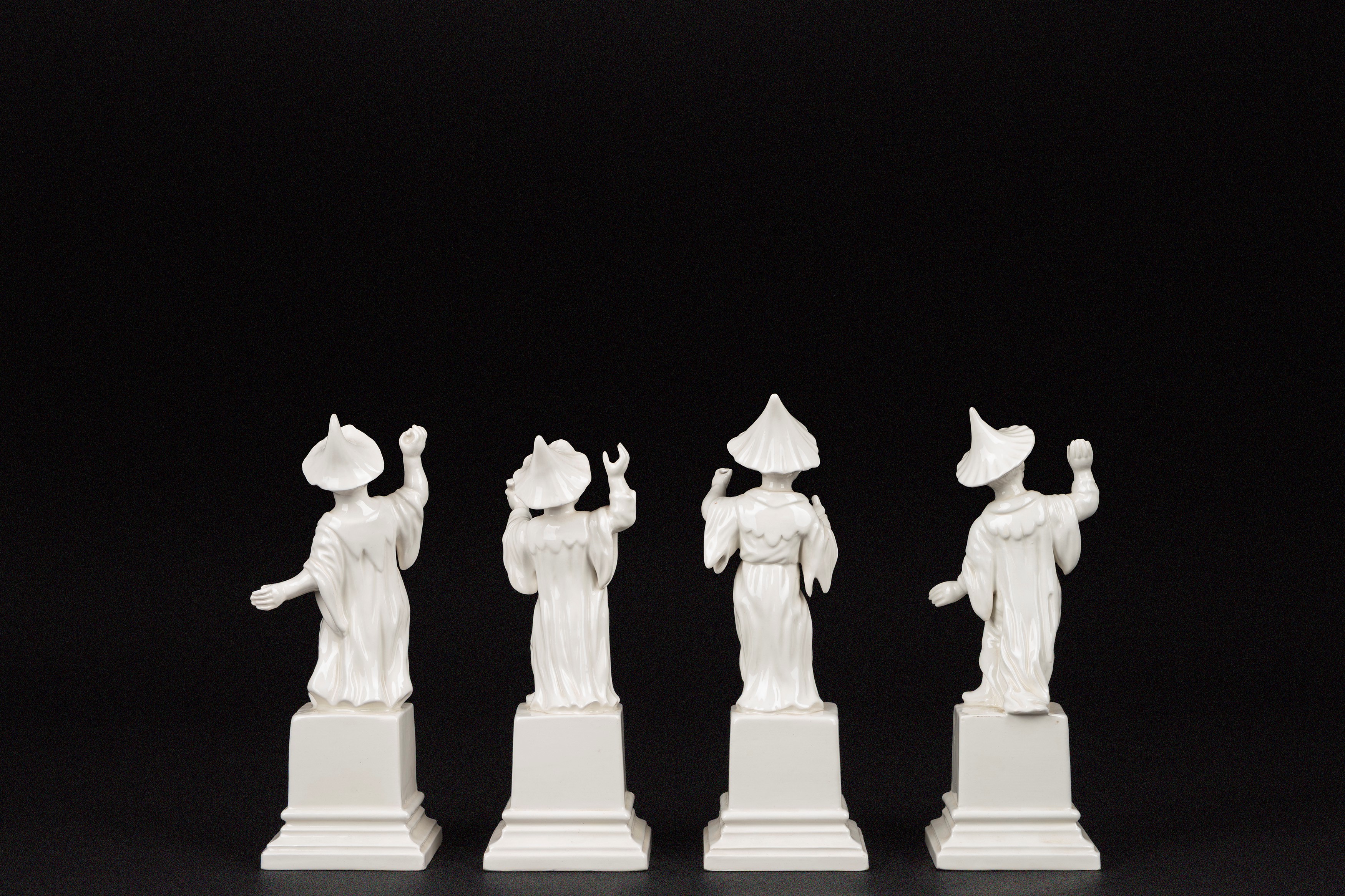 Quattro sculture in porcellana bianca raffiguranti cinesini, su basi a plinto quadrate