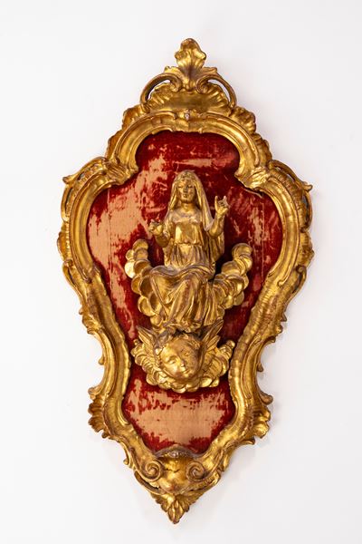 Bassorilievo in legno intagliato e dorato raffigurante la Madonna in gloria su testa di cherubino...
