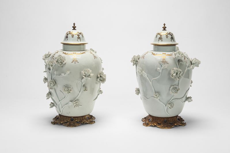 Due potiche in porcellana bianca e dorata con decorazione a rilievo, basi in bronzo dorato (XIX s...