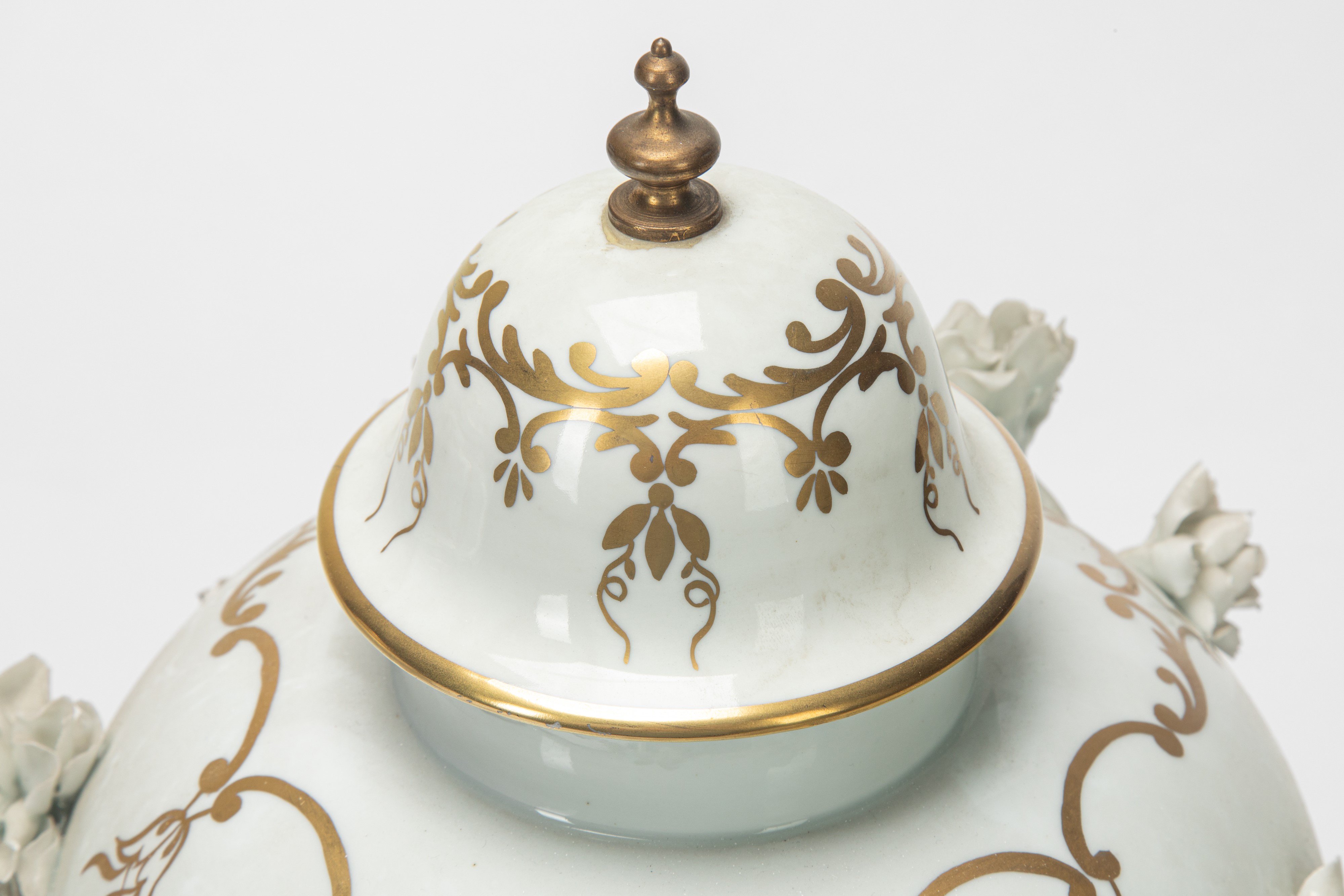 Due potiche in porcellana bianca e dorata con decorazione a rilievo, basi in bronzo dorato (XIX s...