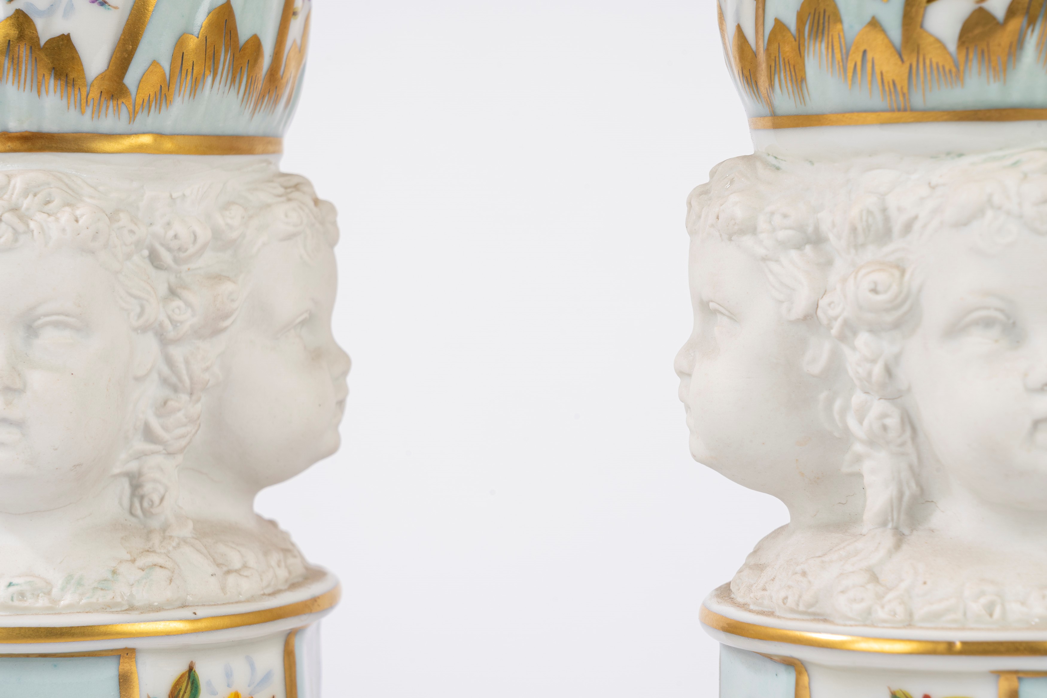 Coppia di vasi in porcellana con teste di putti in biscuit