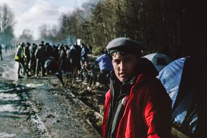Returning from the food distribution point on the disused railway track at the entrance to the camp, which between 2015 and 2016 housed around 2,500 refugees, mostly Kurds, on their way to England. Dunkirk, France