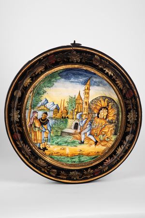 Tito Magrini (Pesaro, 1870 ca. - 1940 ca.) Piatto istoriato in maiolica policroma con scena dantesca. Entro cornice in legno laccato e dipinto a motivi floreali.