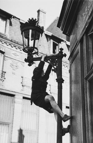 Jeune garcon grimpant sur un rèverbére, Paris