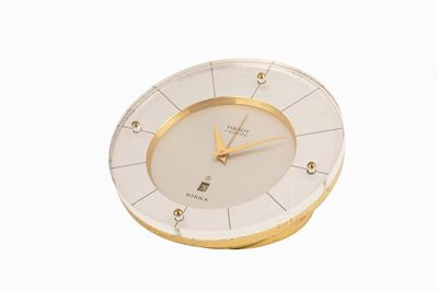 Orologio da tavolo con svegliarino e data, anni '60, cassa cilindrica asimmetrica in ottone dorat...