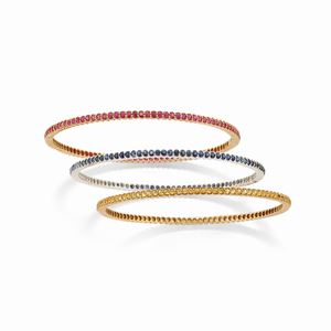 Three two-color gold, ruby and multicolor sapphire bangles